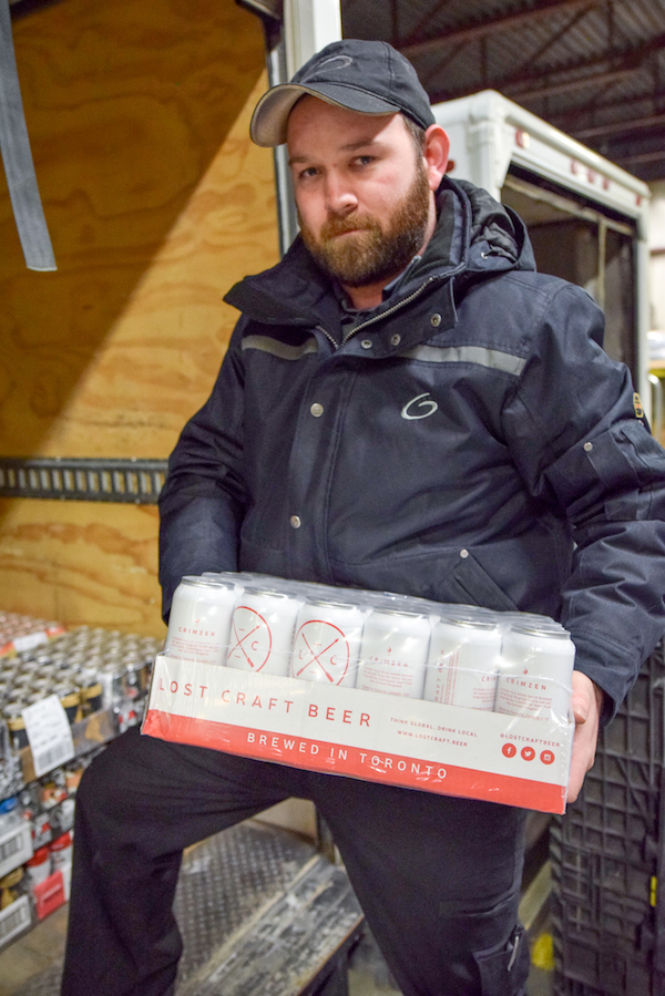 Man unloading case of beer from shipping truck