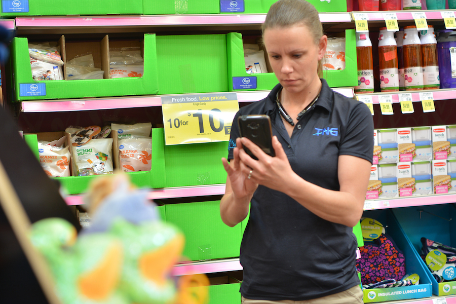 Woman using mobile devices in grocery aisle