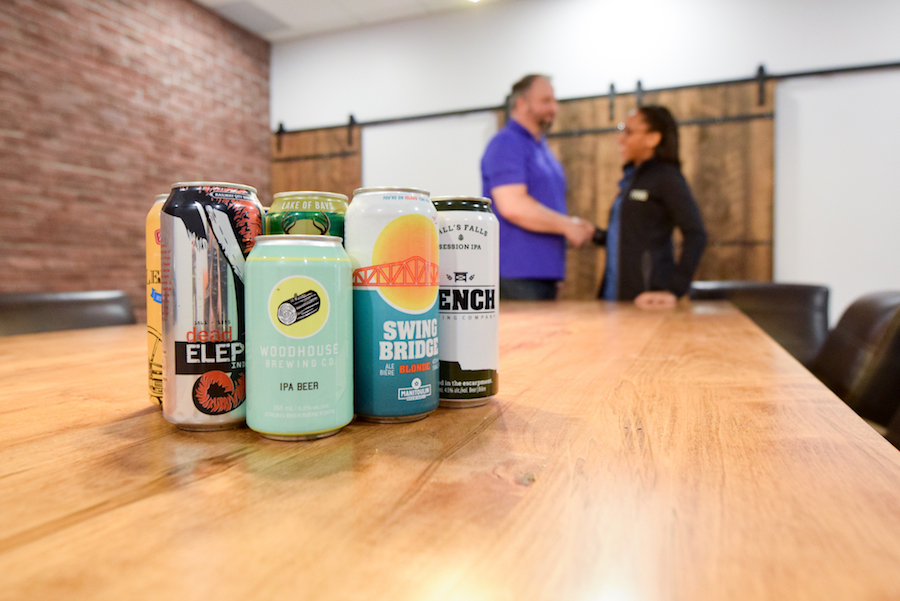 man and woman shaking hands behind cans of craft beer on a table