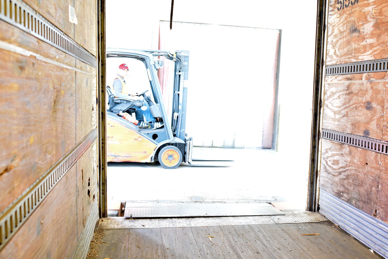 photo of fork lift passing from inside empty shipping truck