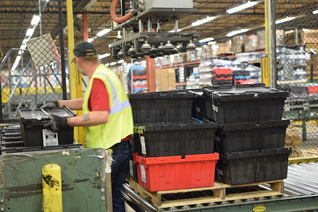 man moving magazine boxes off assembly line in warehouse